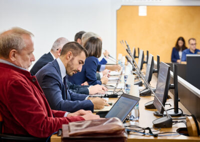 Relatori e partecipanti ai tavoli con microfoni e computer durante il forum Prevenzione in Azione