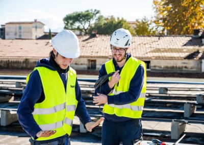 Due tecnici con casco e gilet ad alta visibilità a confronto sul tetto della scuola di Marcianise