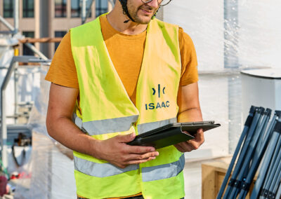 Tecnico ISAAC con gilet ad alta visibilità consulta un tablet nel cantiere in copertura a Milano